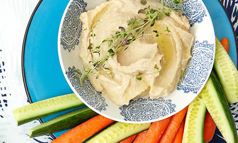 Hvit bønnepostei i skål, toppet med olivenolje og timian. Servert sammen med agurk, gulrot og paprika i stenger.