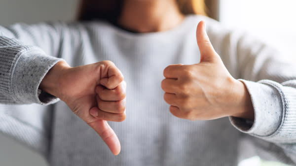 En dame holder en tommel opp og en tommel ned.