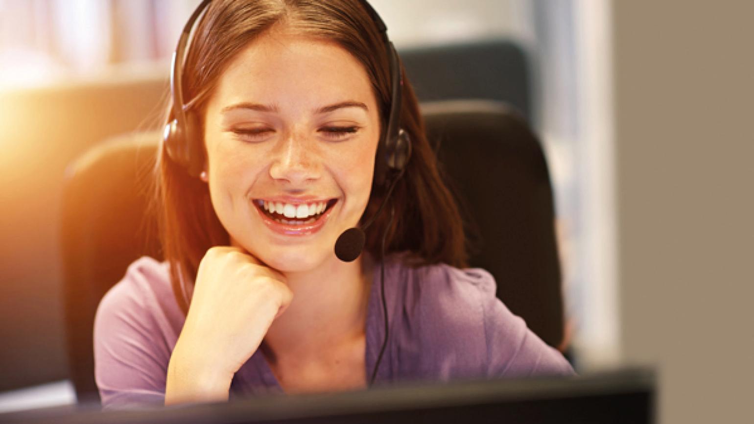 Dame snakker i headset og smiler. 