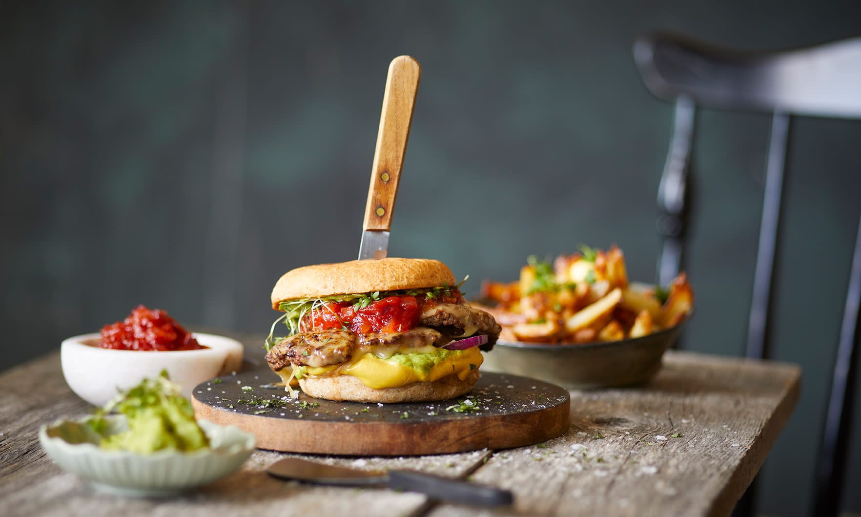 Smashburger med tomatkompott og avokado på bord, servert med sennepsmajones og fries.