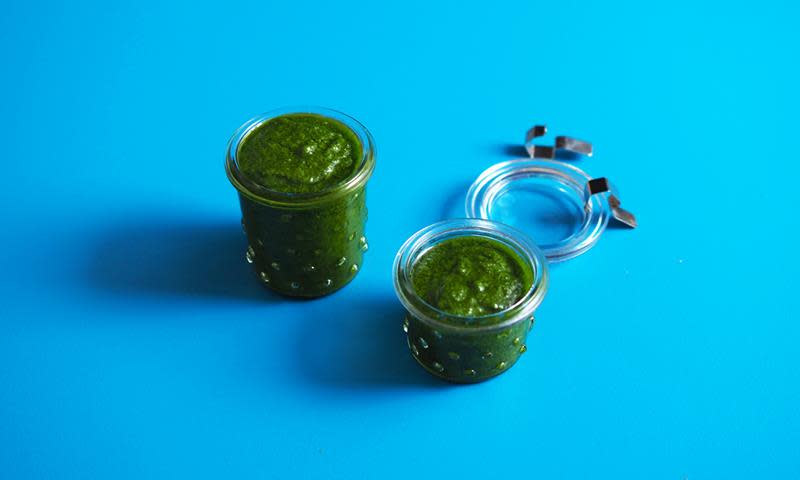 Hjemmelaget pesto av urterester, på to gjennomsiktige glass. Blå bakgrunn.
