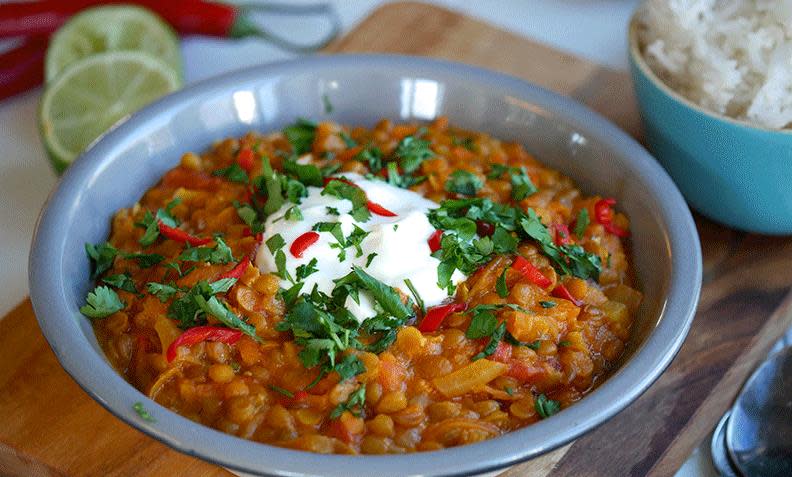 Indisk dal, vegetarisk linsegryte, med løk, linser og chili. Servert i blå skål, toppet med yoghurt, hakket koriander og fersk chili.