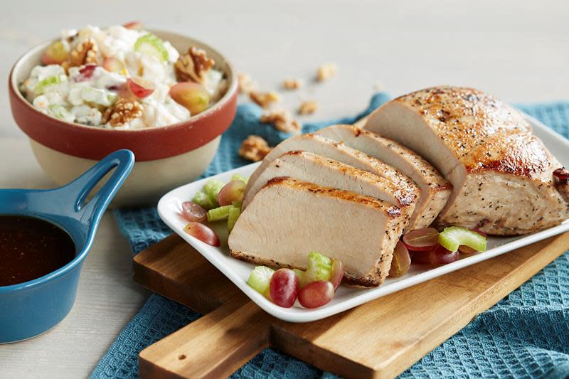 Saftig helstekt kalkunfilet servert på et hvitt fat, med sjysaus og waldorfsalat ved siden av.