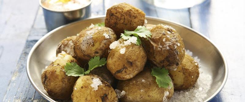 Saltkokte nypoteter servert på metallfat, toppet med salt og persille. Gylden dip ved siden av.