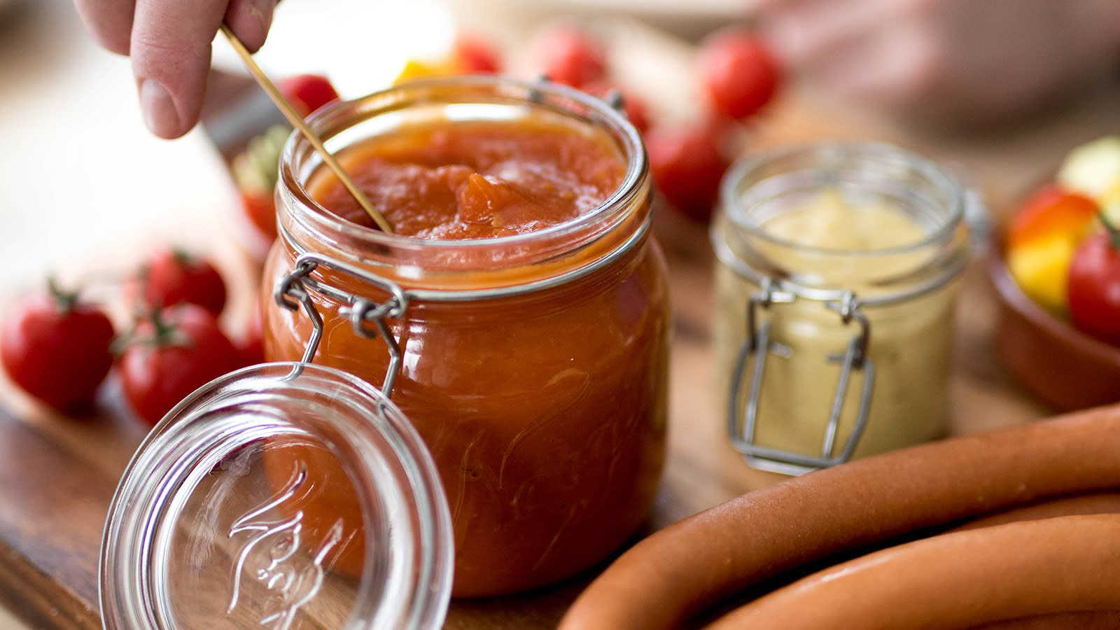 Enkel hjemmelaget ketchup på Norgesglass, servert på trefjøl med wienerpølser og tilbehør.