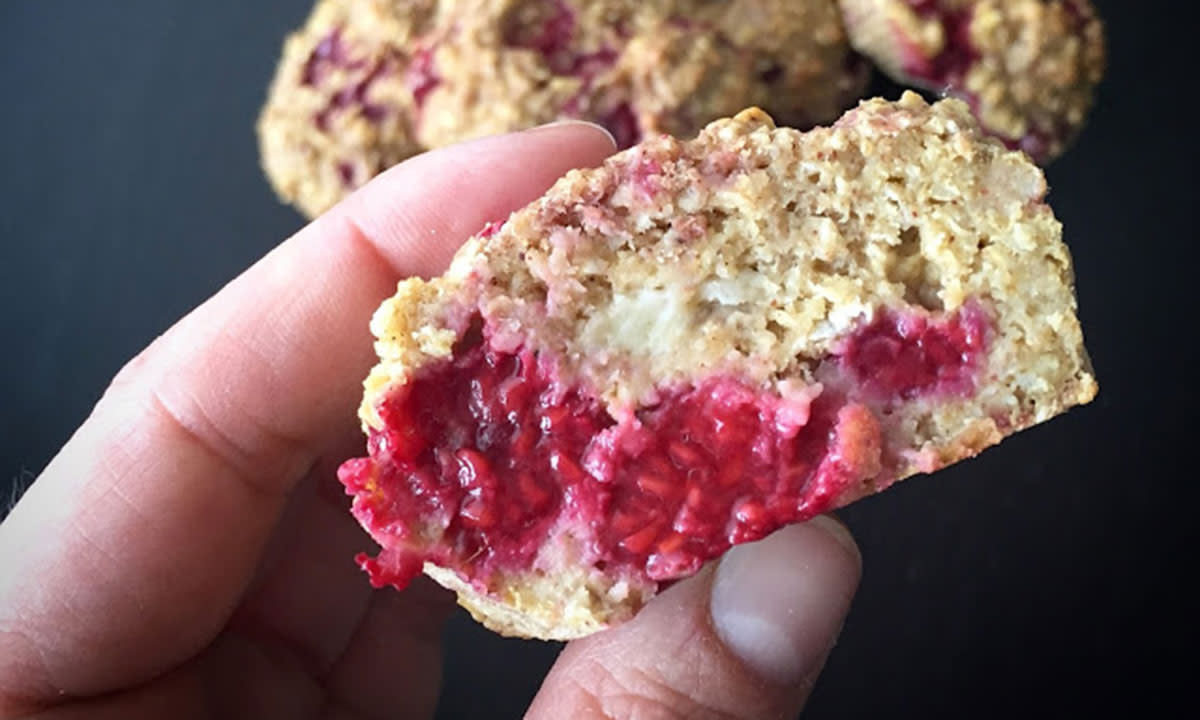 Bringebærmuffins uten tilsatt sukker, delt i to og holdt mellom to fingre for å vise snittflaten med bringebær.