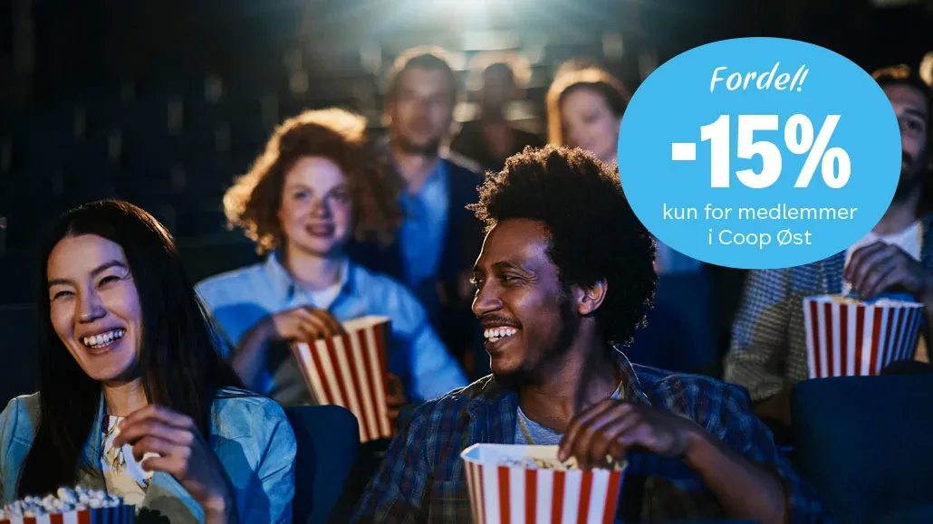 To personer som smiler og spiser popcorn i kinosal.