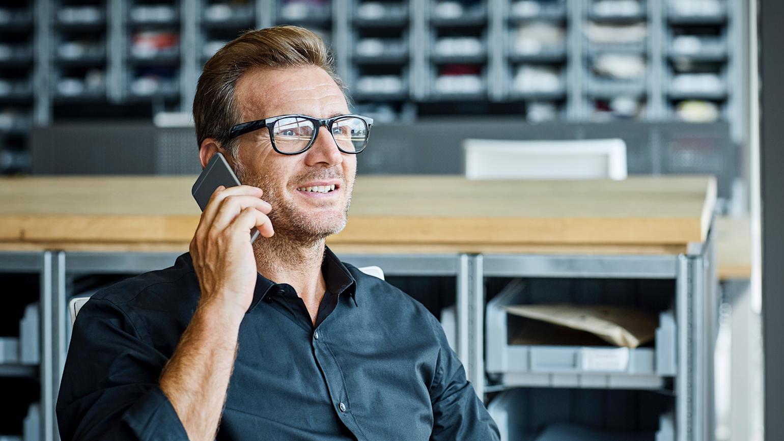 Mann snakker i telefonen og smiler.