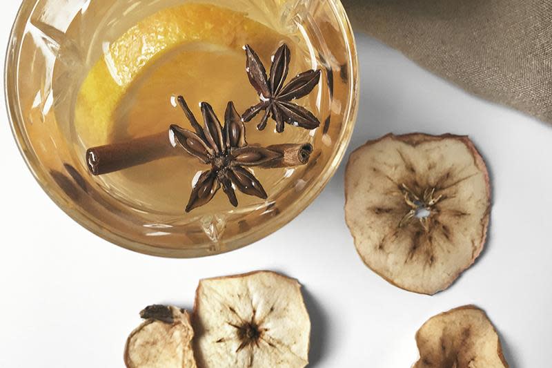 Hjemmelaget eplegløgg med kanel i drikkeglass, pyntet med stjerneanis, tørkede epleskiver og kanelstang.