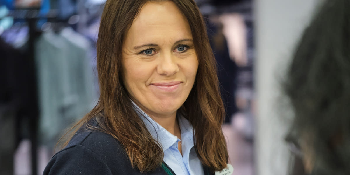 Kvinne i Coop Mega uniform smiler