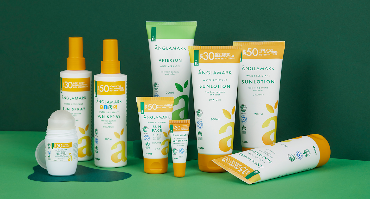 Bildet viser et bredt utvalg av solpleieprodukter fra Änglamark, presentert mot en grønn bakgrunn som fremhever merkets naturlige profil. Produktene inkluderer vannresistente solsprayer, solkremer, aftersun, roll-on solkrem, ansiktskrem og solstift for lepper – alle merket med ulike solfaktor-nivåer fra SPF 15 til SPF 50. Emballasjen er preget av et rent, hvitt design med grønne og gule detaljer og tydelige symboler for UVA/UVB-beskyttelse, vegansk innhold og parfymefri formulering. Produktene er spesielt utviklet for sensitiv hud og barn, og reflekterer Änglamarks fokus på miljøvennlighet og allergivennlige ingredienser.