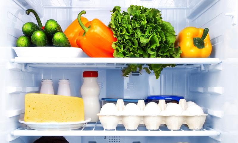 Innsiden av et kjøleskap, med hyller med forskjellige frukt og grønt, samt egg, ost og melk.