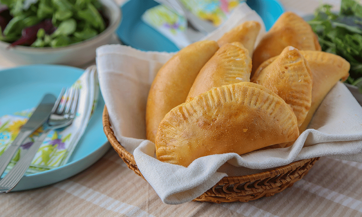 Piroger med kjøttdeig, servert i kurv med hvitt linhåndkle.