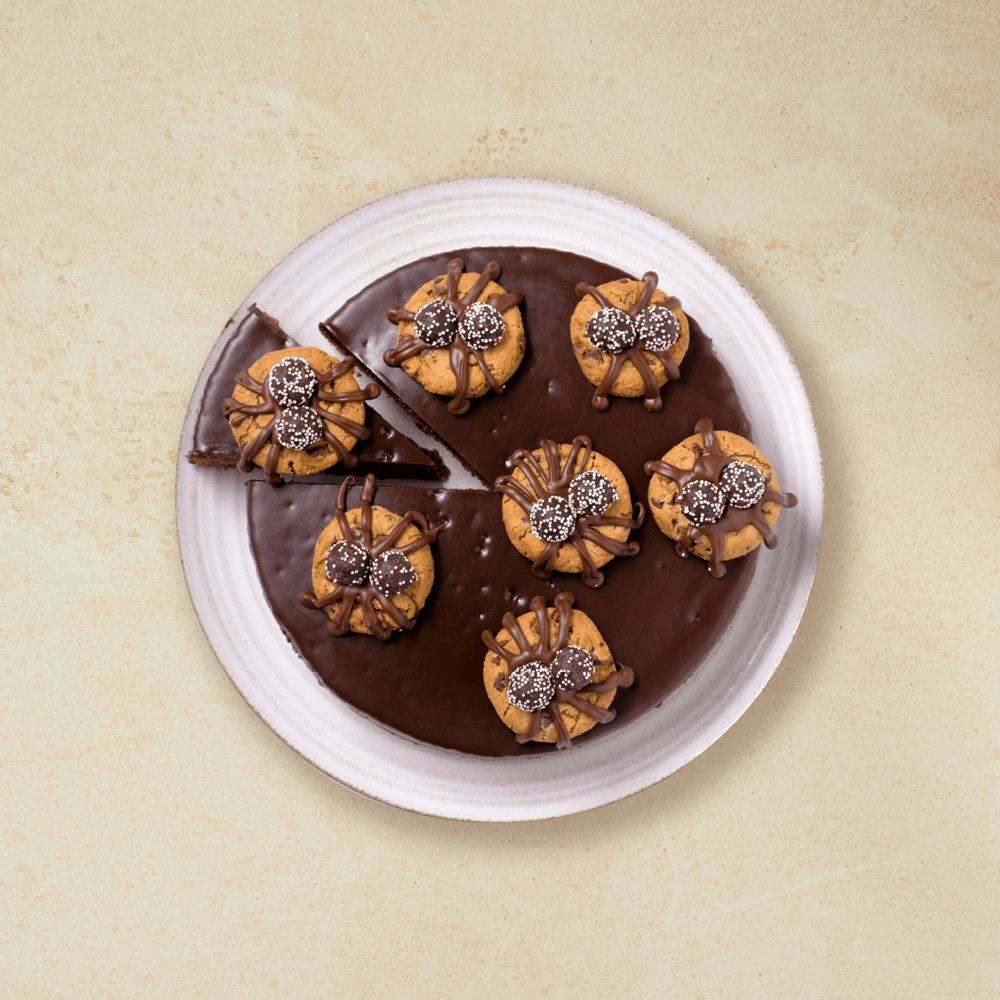 Skummelt god Halloweenkake; sjokoladekake med kjeks på toppen som er pyntet med godteri og glasur som skal forestille edderkopper