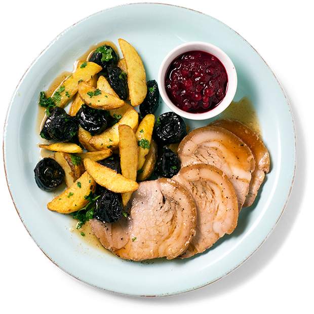 Skinkestek, potetbåter og svisker på en lyseblå tallerken med et glass tyttebærsyltetøy. Hvit bakgrunn.