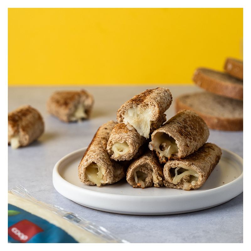 Ostesticks stablet i pyramideform på hvit tallerken. Skiver grovbrøpd i bakgrunnen.