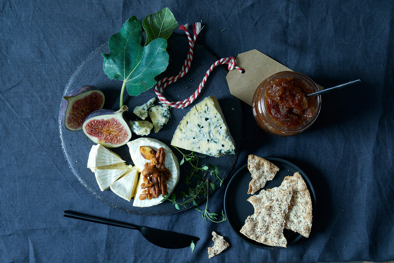 Hjemmebakt knekkebrød med rosmarin servert til ostefat med spennende oster og ferske fiken. Fikenmarmelade ved siden av.