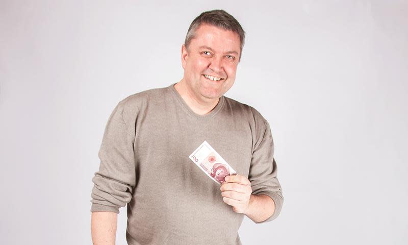 Gjerrigknarken Rune Nikolaisen holder opp en 100-lapp og smiler.