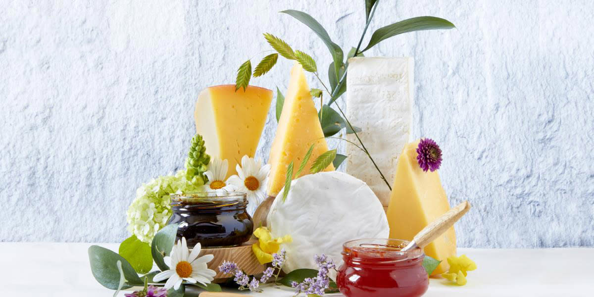 Ostestykker stablet på bordplate med blomster og syltetøy rundt