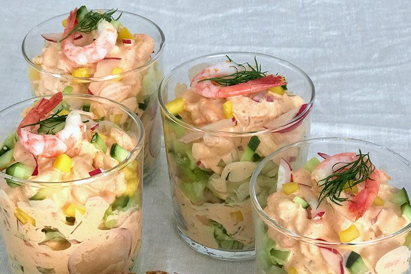 Rekecocktail på glass med agurk, mango, reddik og hjemmelaget saus. Dandert med ferske reker og dill. Lys bakgrunn.