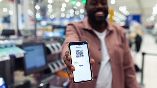 Mann viser frem coop appen for scanning av medlemskort på mobilen