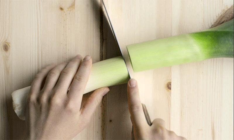 Hel purre delt i to ligger på trefjøl, hender holder i purren og i en kniv.