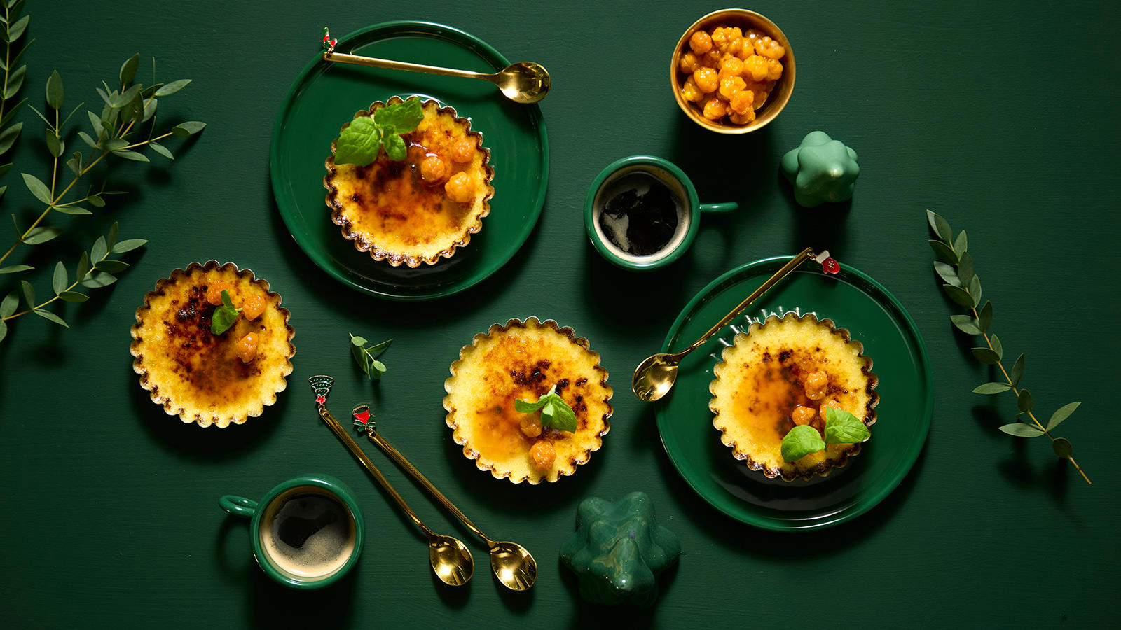 Riskrem brûlée med multesaus servert på mørkegrønne asjetter med gullskjeer og grønne kaffekopper.
