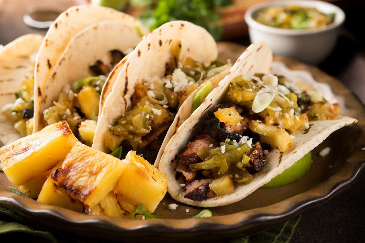 Grillet mango- og ananassalsa over kjøtt i tacolefser, servert på fat.