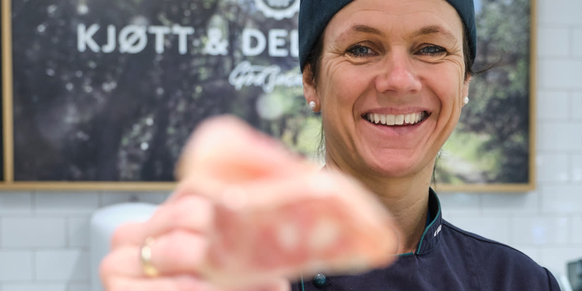 Ferskvaremedarbeider i Coop Mega viser frem produkter og smiler