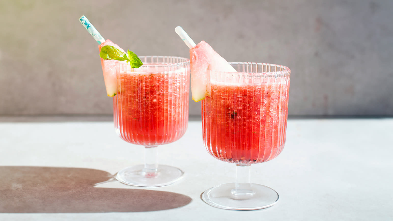 Vannmelon slush i to stettglass med vannmelon og friske urter, servert i sommerlys.