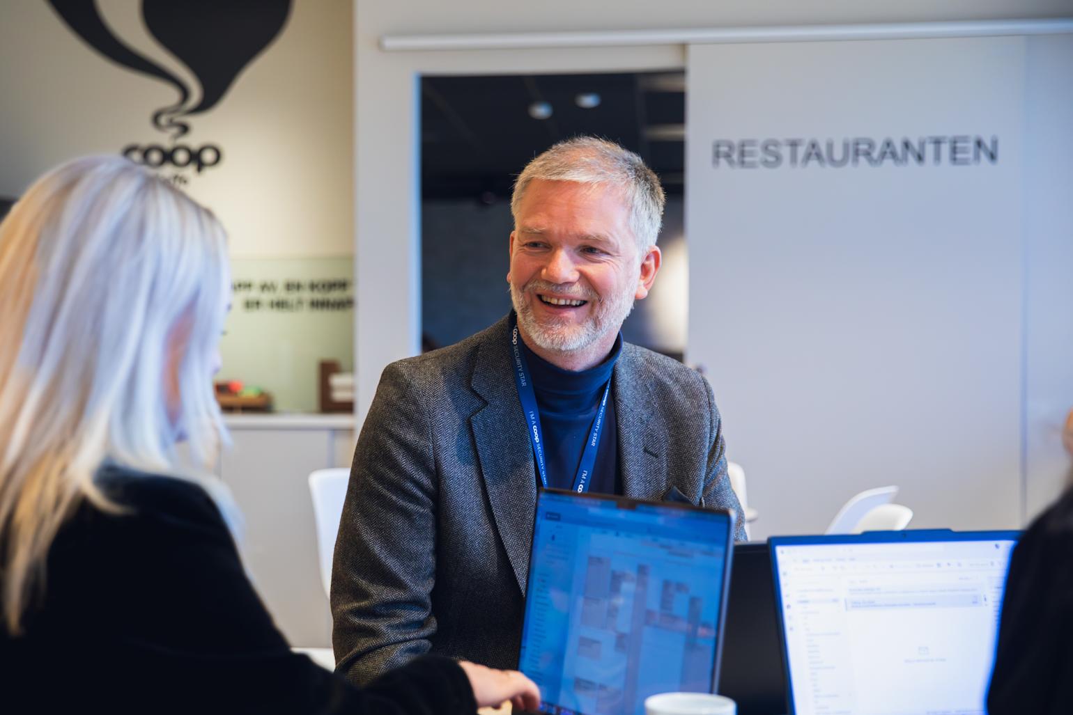 Mann smiler i kaffebaren