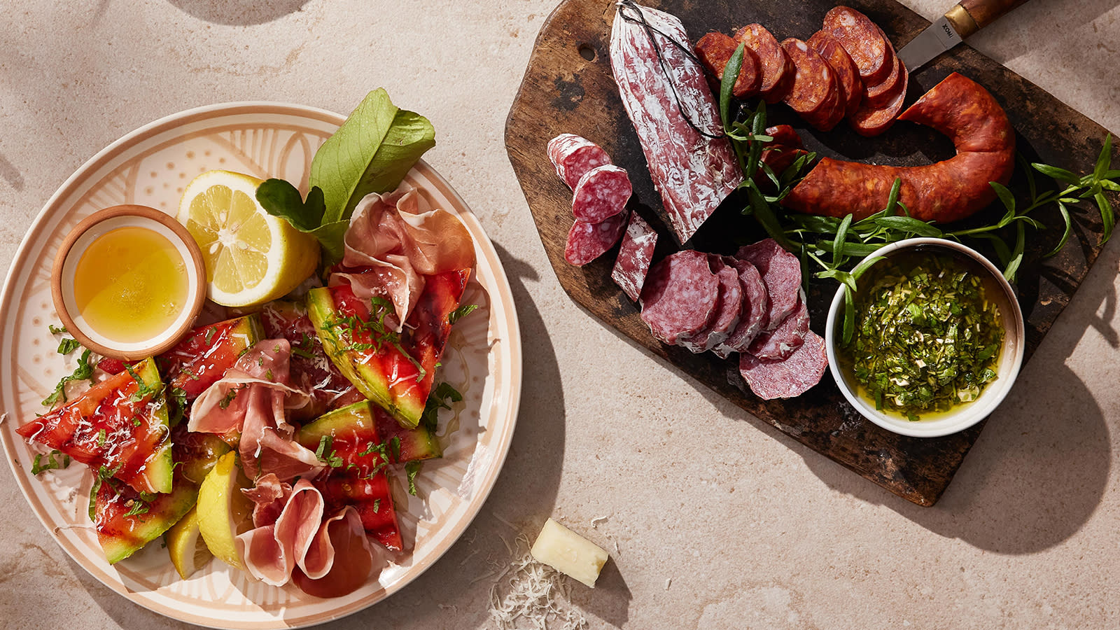 Grillet vannmelon med serrano og manchego servert på mønstret lyst fat med olivenolje, sitronbåter og friske urter. Fat med spekemat ved siden av.