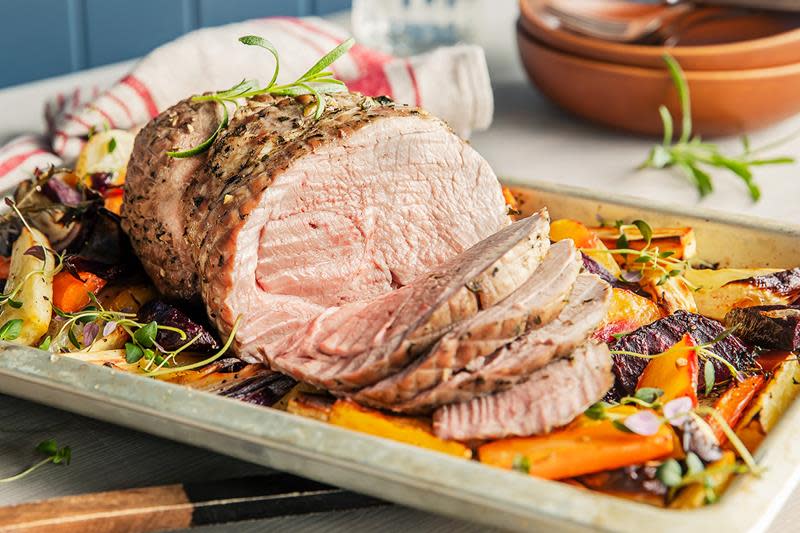 Saftig lammestek på seng av fargerike rotgrønnsaker. Servert på fat, og toppet med fersk rosmarin.