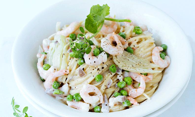 Pasta i form av spagetti, med kremostsaus og reker, erter og fennikel, i hvit dyp tallerken.