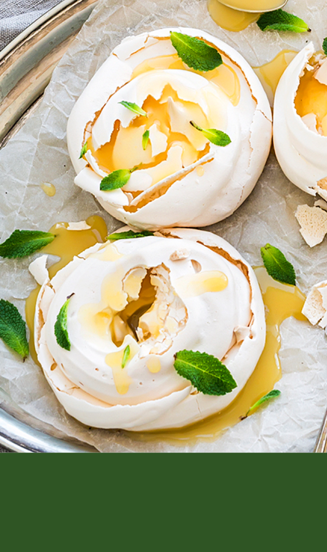 Mini pavlova kaker på fat øverst og grønn bakgrunn nederst