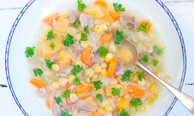 Ertesuppe med saltkjøtt, gule erter, gulrøtter, kålrot og selleri servert i hvit suppetallerken med blå kant.