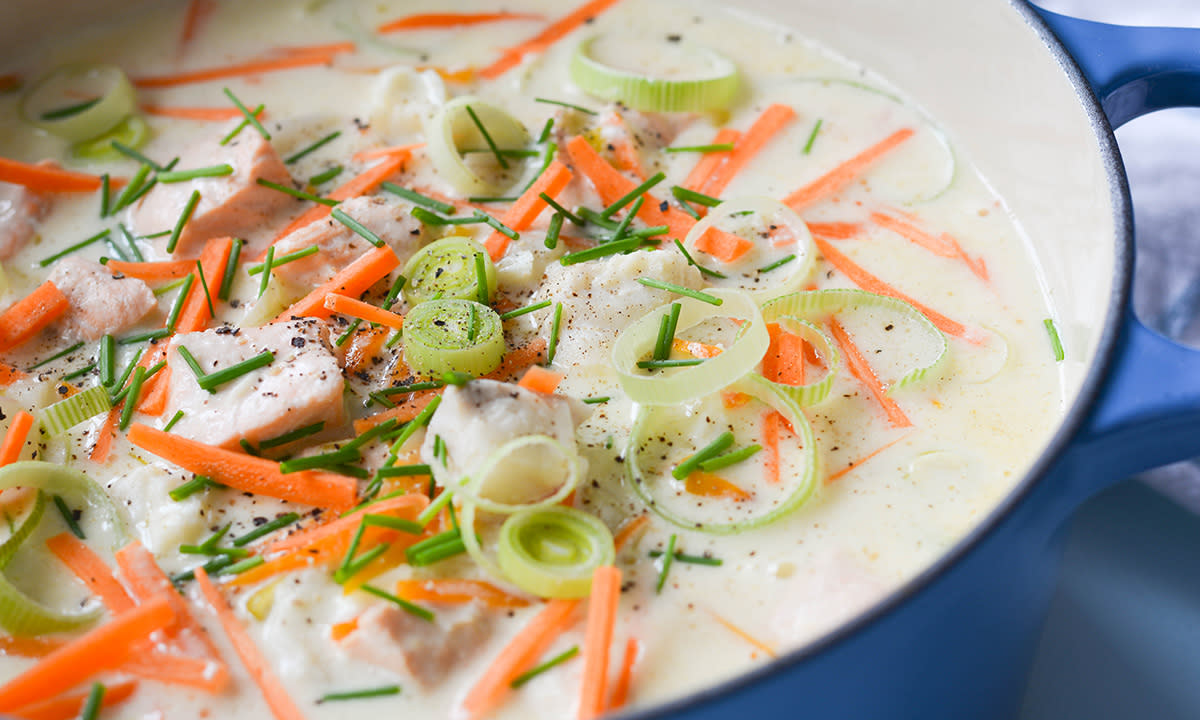 Fiskesuppe med gressløk, gulrot, fisk, salt og pepper, i en blå kjele