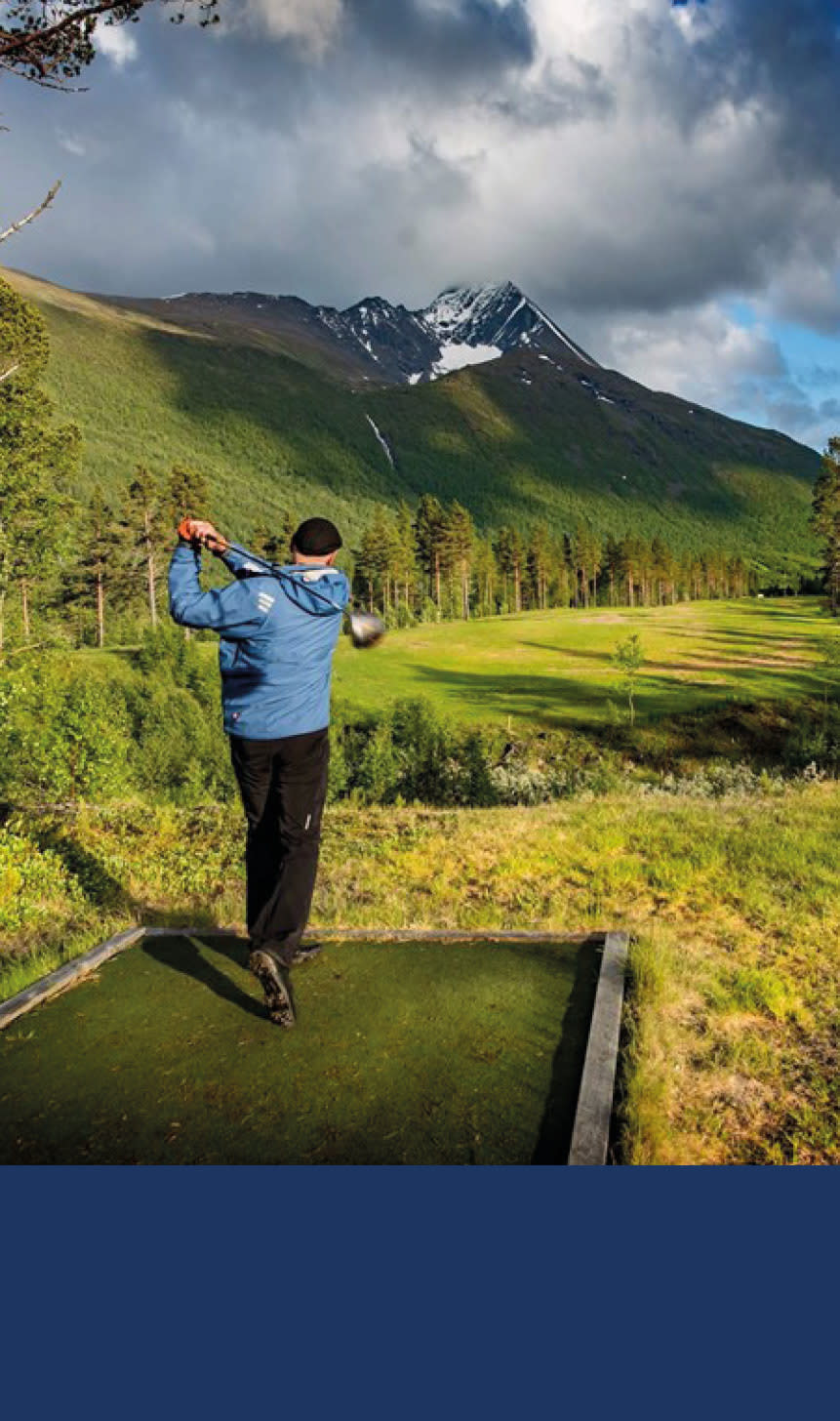 Bilde av en mann som slår med en golfkølle med fin natur i bakgrunnen.