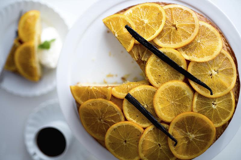 Appelsinkake med kandisert appelsin, pyntet med vaniljestang og servert på hvitt stettfat.