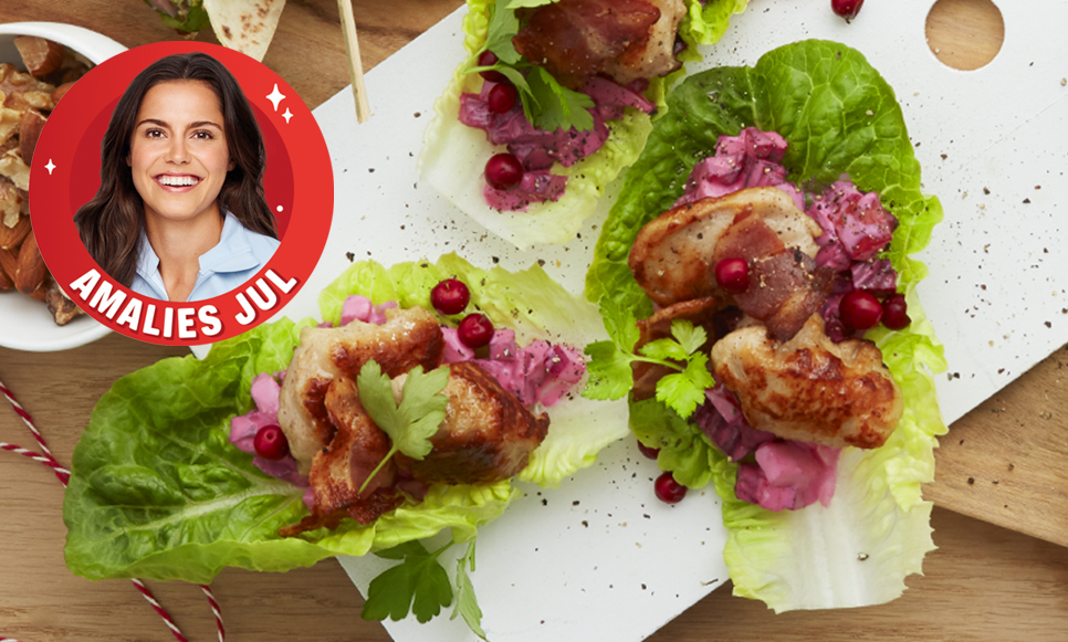 Salatwrap med medisterboller og hjemmelaget rødbetesalat, servert på hvit trefjøl på lyst trebord. Salatwrappene er pyntet med ferske tyttebær og sprøstekt bacon.