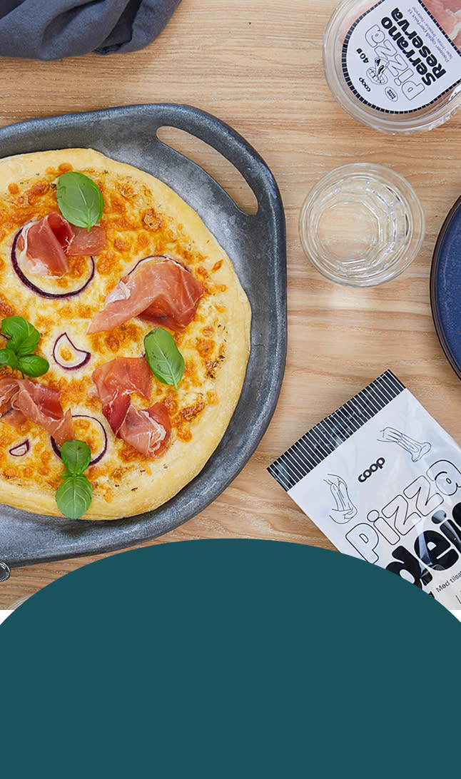 Et dekket bord med en serrano-pizza i midten og ulike Coop Pizza-produkter rundt.