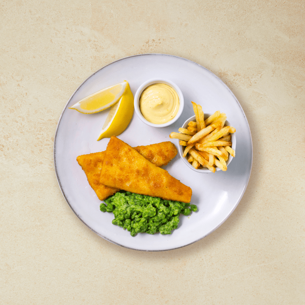 Fish and Chips med ertestuing, majones i skål og sitronbåter på hvit middagstallerken