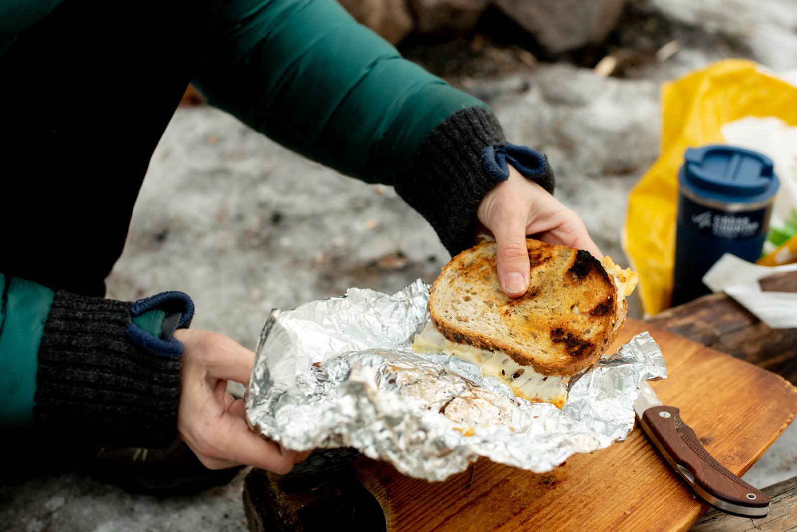 Toast med ost og skinke - på bålet, trekkes ut av aluminiumsfolie på skjærefjøl i tre. 