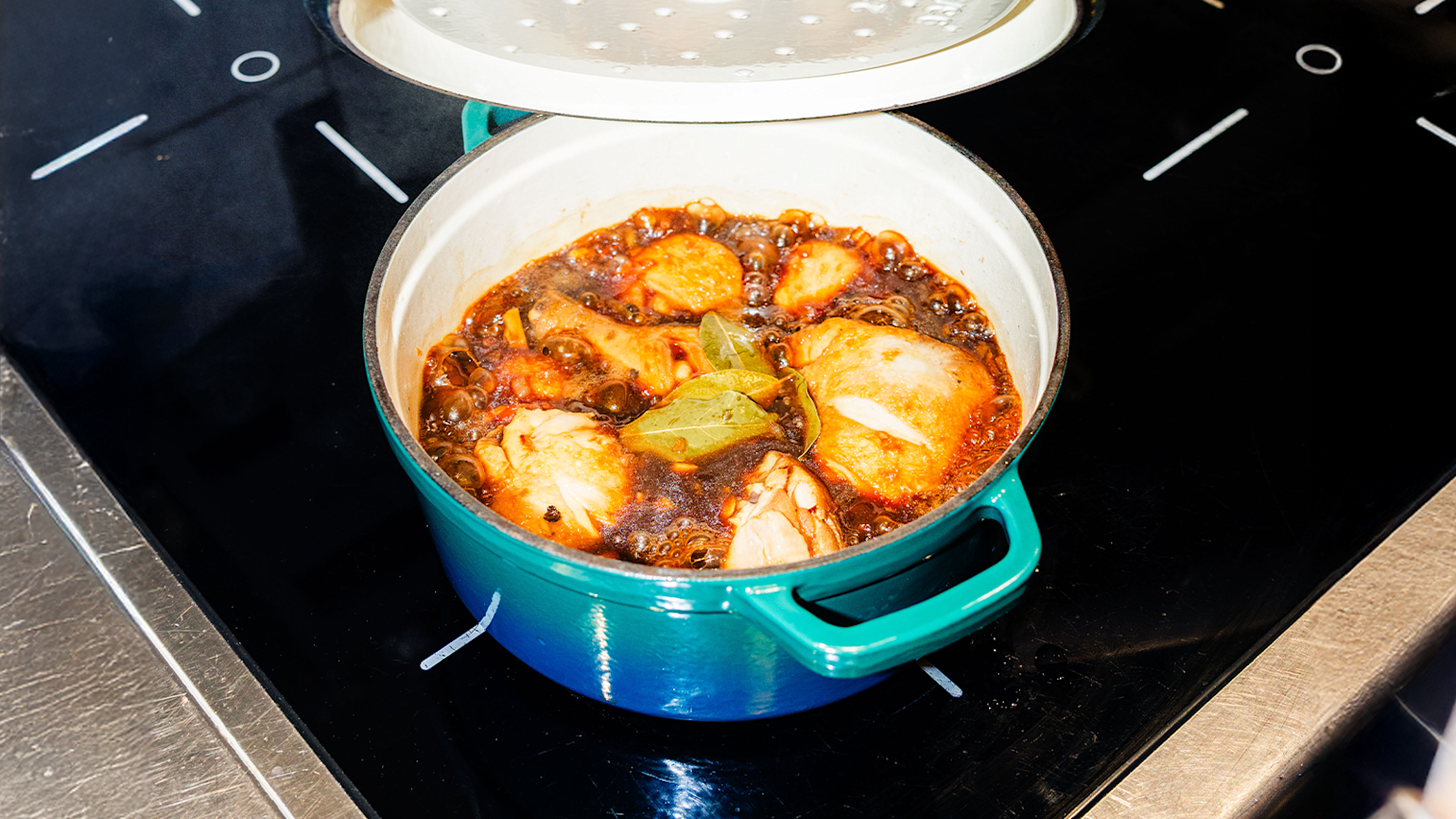 Asiatisk mat, kylling i en rund blå gryte på en koketopp.