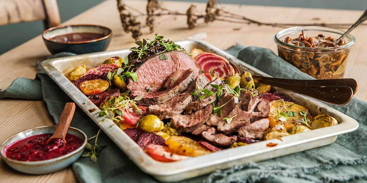 Elgstek skåret i skiver, og servert å fat. På fatet ligger også ovnsbakte beter i skiver, rosenkål og frisk timian. Tyttebærsyltetøy, syltet sopp og rødvinssaus i skåler ved siden av.