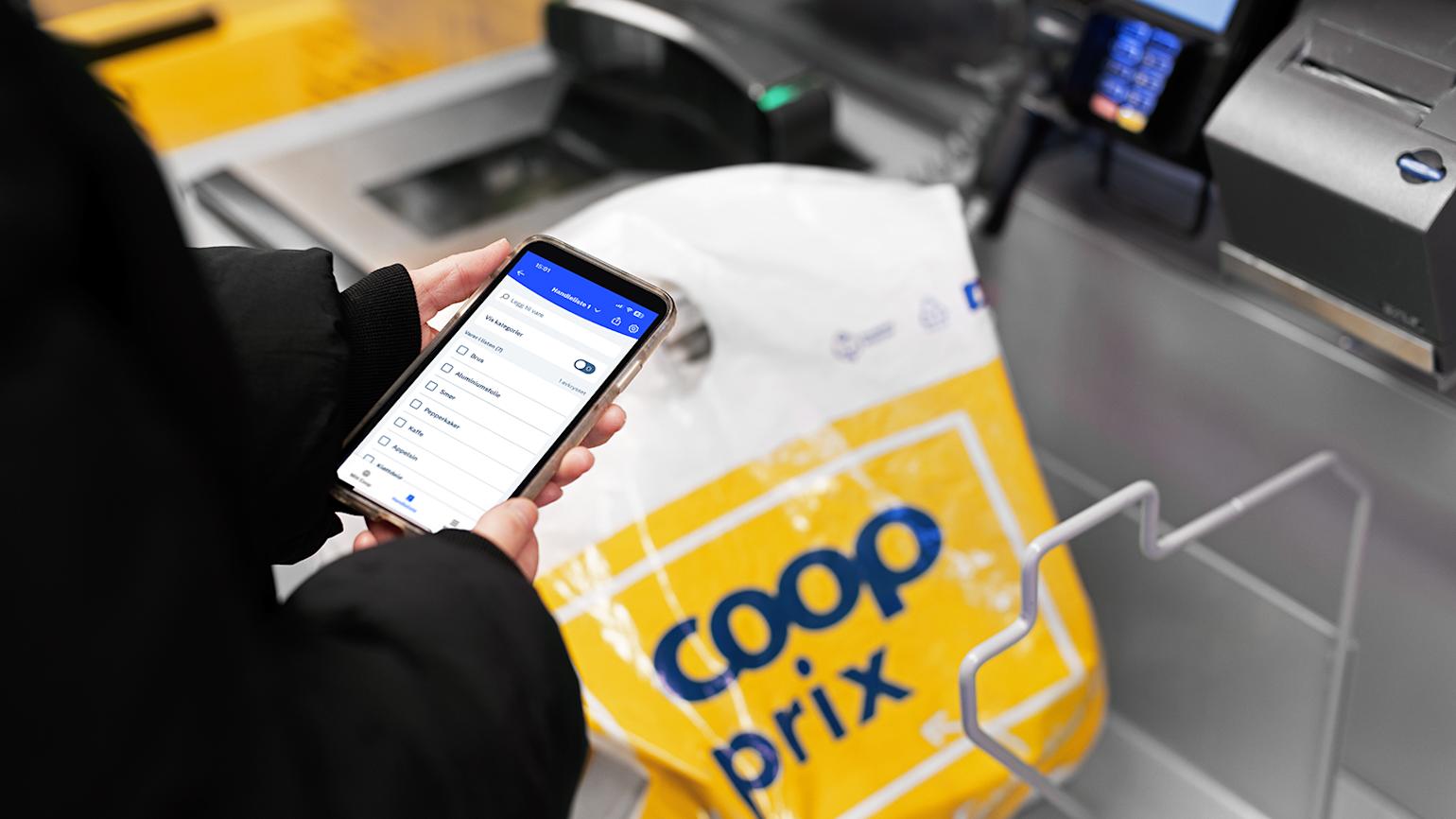 Coop Prix - Kvinne sjekker handlelisten i appen mens hun står i selvbetjent kasse