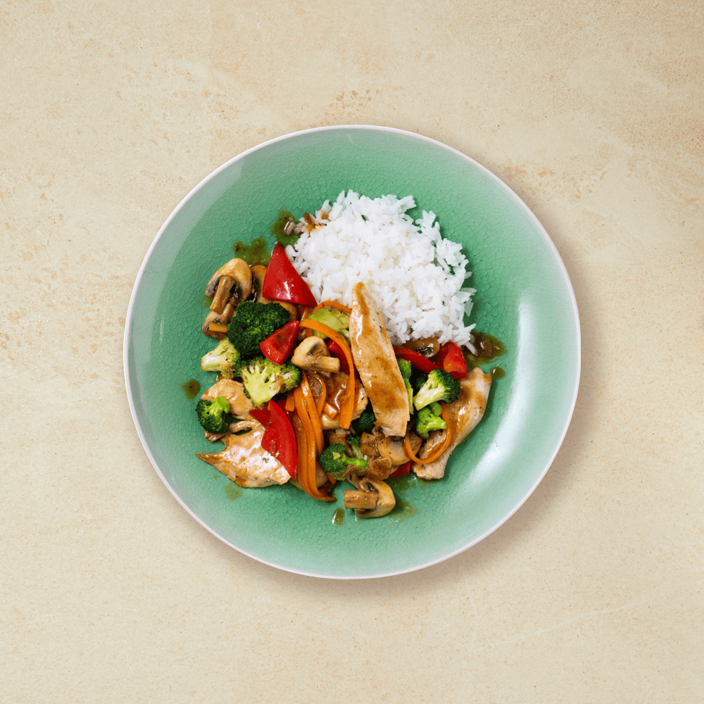 Kyllingwok med paprika, brokkoli, gulrøtter og ris i en lysegrønn skål.