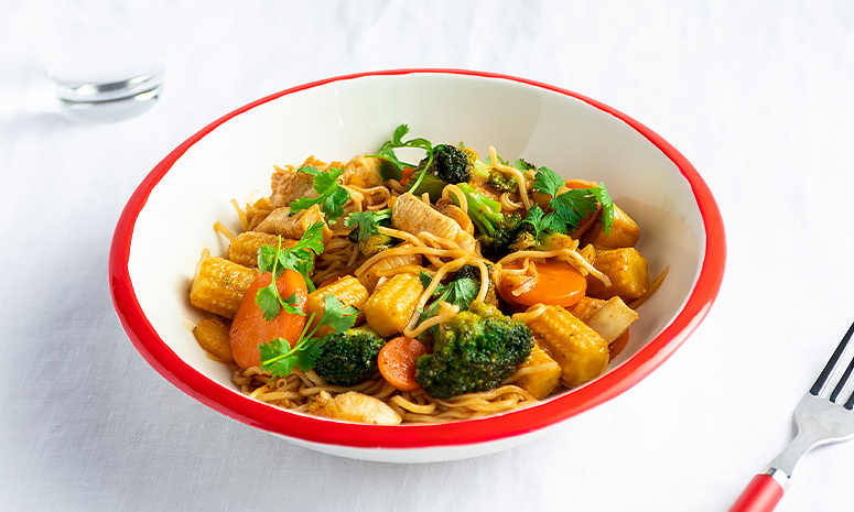 Wok med kylling og nudler i dyp hvit tallerken med rød rand