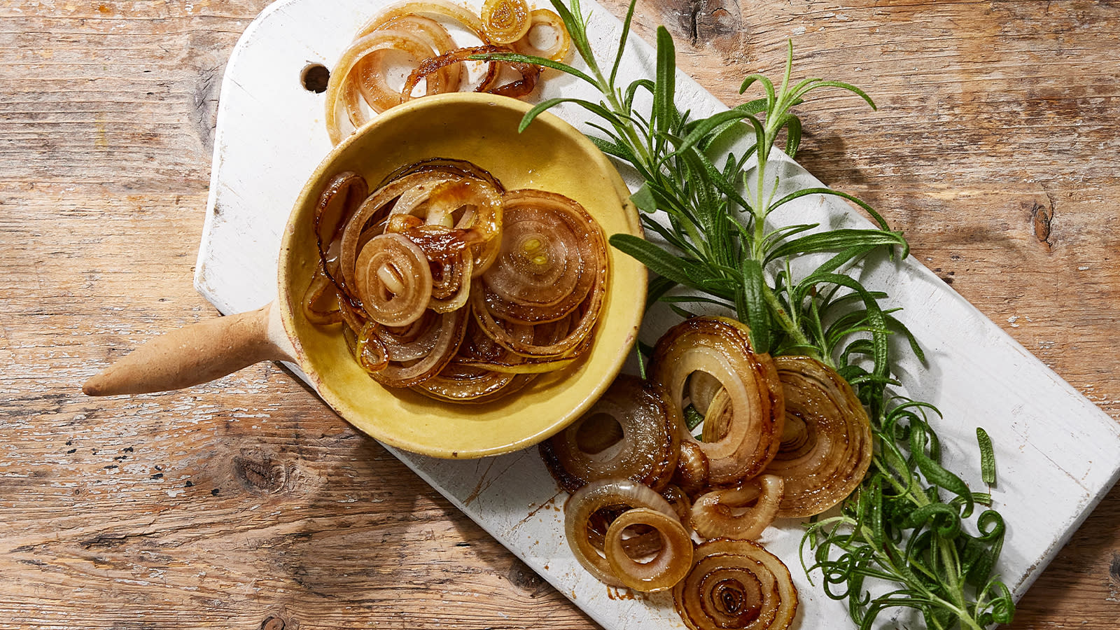 Grillet og karamellisert løk servert i gul skål på rustikk trebord.