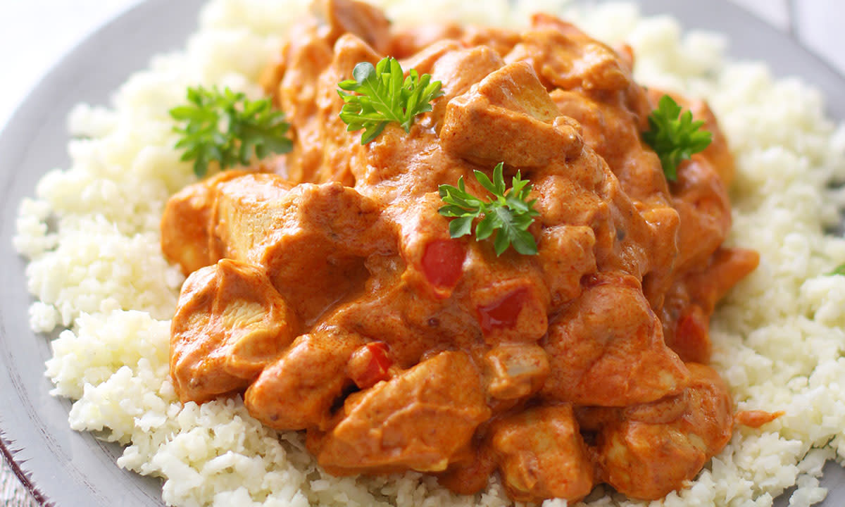 Kylling tandoori med blomkålris pyntet med persille på en grå tallerken.